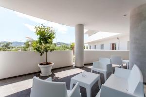 维耶斯泰西亚利酒店的阳台配有白色椅子和盆栽树