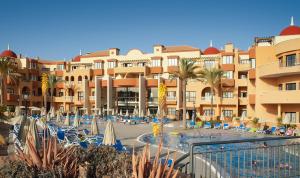 圣米格尔德阿沃纳Grand Muthu Golf Plaza Hotel & Spa的一个带椅子和棕榈树的游泳池的度假酒店