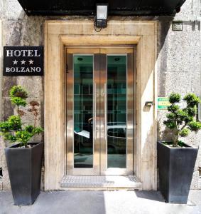 米兰伯尔扎诺酒店的门前有两棵盆栽植物的酒店的门