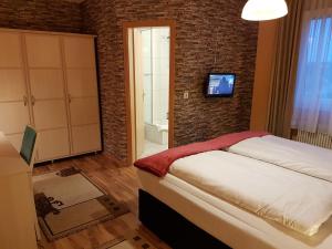 比伯斯海姆飞天大酒店 的卧室配有1张床和1台砖墙电视