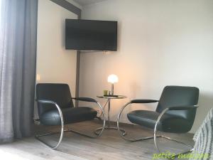 吕讷堡petite maison的一间设有两把椅子和一张桌子的房间,墙上配有电视