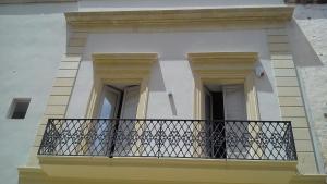 加拉蒂纳Kaleidos Guest House的带阳台的建筑,设有两扇门和栏杆