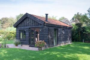 迪弗尔Vakantiehuisje met bedstee的一座带绿色草坪的小木房子