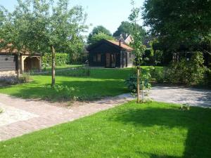 迪弗尔Vakantiehuisje met bedstee的一座带绿树成荫的庭院和车道的房子
