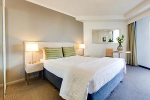 布里斯班Oakbridge Hotel & Apartments Brisbane的卧室配有一张白色大床和镜子