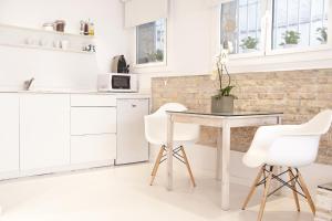 锡切斯Studio Relax by Hello Homes Sitges的白色的厨房配有桌子和白色椅子