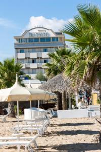 里米尼日光酒店的海滩上的酒店,设有椅子和棕榈树
