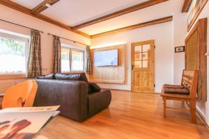 罗孚尔Alte Zimmerei - Lofer的客厅配有真皮沙发和电视