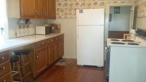 普廷贝Aunt Jane's Yellow House的厨房配有白色冰箱和木制橱柜。