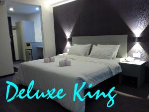 麻坡麻坡商贸酒店的一间卧室配有一张白色大床,拥有蓝色的灯光
