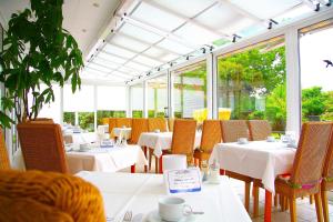 朗格奥弗洛科酒店的餐厅设有白色的桌椅和窗户。
