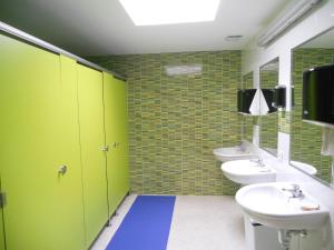 圣地亚哥－德孔波斯特拉Albergue la Estacion Santiago de Compostela的绿色浴室设有两个水槽和两个卫生间