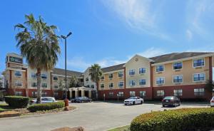 休斯顿Extended Stay America Select Suites - Houston - Willowbrook - HWY 249的停车场内停放汽车的大型建筑