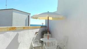 莱乌卡Villa La Floridiana - Sweet House的阳台上配有带遮阳伞和椅子的桌子