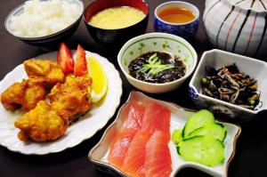 宫古岛Pension Orange Box的餐桌上摆放着盘子,上面放着寿司和蔬菜