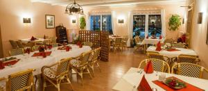 托尔高Hotel Torgauer Brauhof的餐厅配有白色的桌椅和红色的餐巾
