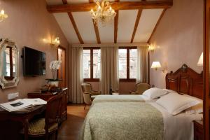 威尼斯比三兹奥酒店的一间卧室配有一张床、一张书桌和一台电视
