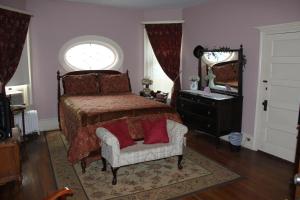 TowandaVictorian Charm Inn的一间卧室配有一张床、一把椅子和镜子