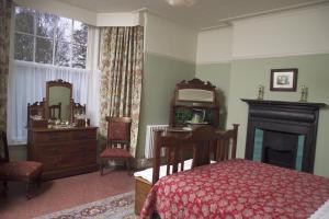 斯旺西狄兰托马斯乡村民宿的一间卧室配有一张床、一张书桌和一面镜子