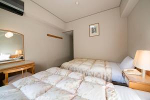 本宫山水馆川汤松屋酒店的一间卧室配有两张床、一张桌子和一面镜子
