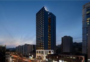 首尔Shilla Stay Seocho Gangnam Station的一座高大的建筑,城市里灯火通明