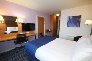 纽尼顿纳尼顿假日快捷酒店的配有一张床和一张书桌的酒店客房