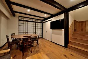 京都Machiya Kamo River 7的一间带桌椅和电视的用餐室