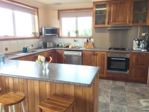 彭古因企鹅海滨民宿的厨房配有木制橱柜和台面
