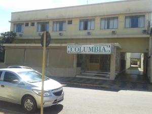 皮拉苏农加Hotel Columbia Palace的停在有街标的建筑前面的汽车