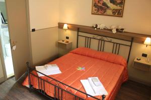 诺尔恰Albergo Benito的一间卧室配有橙色床,里面放着两本书