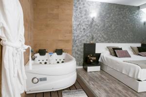 圣拉菲尔芬卡拉卡索纳高级客房酒店的卧室旁配有床和浴缸的浴室