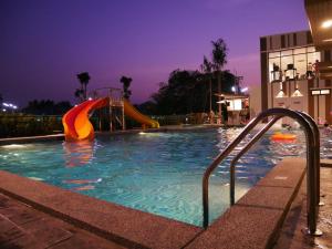 达叻府达勒城市酒店的游泳池在晚上,有滑梯