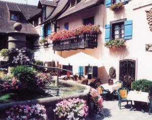 埃圭斯海姆Auberge du Rempart的一座带桌椅的庭院和一座鲜花盛开的建筑
