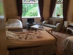 MarpleOakfield Lodge Guest House Stockport的一间卧室配有一张床、一张沙发和一个窗口