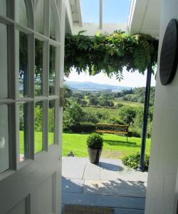波特马多克Plas Tan-Yr-Allt Historic Country House & Estate的通往门廊的开放式门,享有长凳的景致