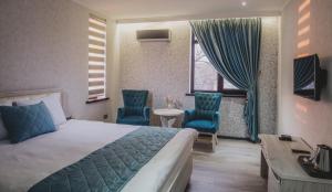 塔什干格鲁普阿斯特酒店的酒店客房,配有一张床和两张蓝色椅子