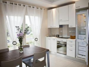 阿克拉艾克西斯套房公寓的厨房配有白色橱柜和花瓶桌子