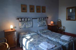 ScorgianoAgriturismo Scorgiano的一间卧室配有两张床、两张桌子和两盏灯。