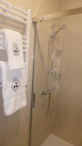 瓜达卢佩塞雷佐旅馆的一间带毛巾和玻璃门淋浴的浴室