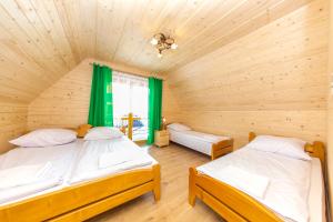 苏凯Góralskie Zacisze Domki的配有绿窗帘的木制客房中的两张床