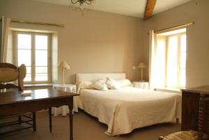 比涅维勒Les Chambres d'hôtes Benoit Breton的一间卧室配有一张床、一张书桌和两个窗户。