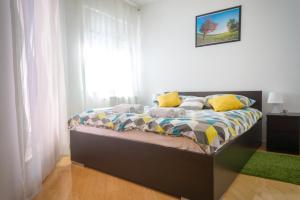 萨格勒布Blue Lake Apartment的一间卧室配有一张带黄色枕头的床和一扇窗户