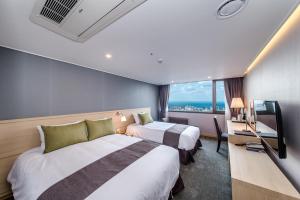 济州市济州萨洛酒店的酒店客房设有两张床和电视。