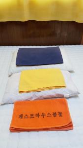 西归浦市春之繁花旅馆的一张带三个枕头和两个垫子的床