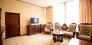 特尔古穆列什帝国酒店的一间带椅子、电视和桌子的房间