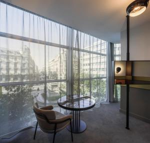 格拉纳达Hotel Colón Centro的客房设有桌椅和大窗户。