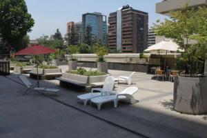 圣地亚哥La Gloria 30. Las Condes的庭院配有白色的桌椅和遮阳伞。