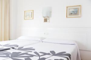 圣地亚哥－德孔波斯特拉Rey Fernando的一张白色的床,上面有黑白毯子