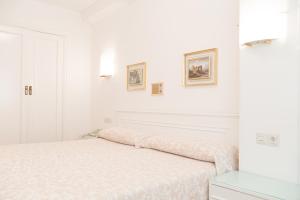 圣地亚哥－德孔波斯特拉Rey Fernando的白色卧室配有一张床,墙上挂有两张照片