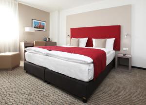 卡塞尔瑞斯卡塞尔金色郁金香酒店的一间卧室配有一张大床和红色床头板